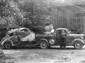 Black and White photo of Harry Weller standing in front of the first Weller Auto Parts truck.